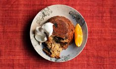 a white plate topped with muffins covered in cream next to an orange slice