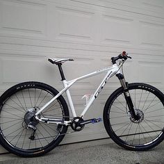 a white mountain bike parked in front of a garage door