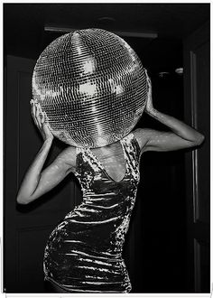 a woman is holding a disco ball on her head