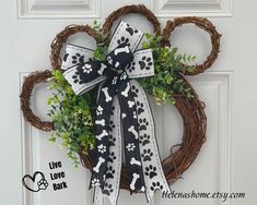 a dog paw wreath on the front door with live love bark written on it and black and white ribbon