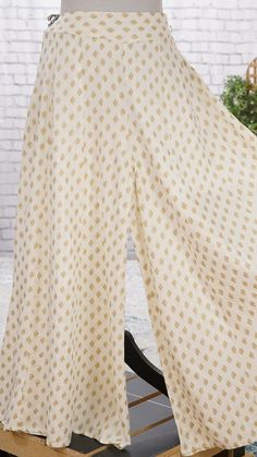 PRODUCT DETAILS A pair of Off-white and golden printed woven flared Palazzos, has a partially elasticated waistband, opaque, 1 pocket (Gold Print may vary slightly depending on the size) Size & Fit Size: S Waist: 30 inches (expandable upto 36 inches) M Waist: 32 inches (expandable upto 48 inches) L Waist: 34 inches (expandable upto 40 inches) XL Waist: 36 inches (expandable upto 42 inches) XXL Waist: 38 inches (expandable upto 44 inches) Palazzo Length: 39 inches Material & Care Liva Dry Types Of Palazzo Pants, Palazzo Pants Outfit Indian Casual, Traditional White Wide Leg Bottoms, Traditional White Bottoms For Festive Occasions, Traditional White Wide Leg Sets, Gold Wide Leg Bottoms For Summer, Gold Wide Leg Bottoms For Festive Occasions, Festive Ankle-length Bottoms For Festivals, Traditional Gold Pants For Festive Occasion