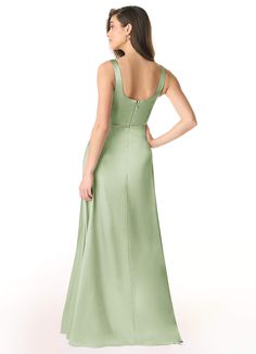 a woman in a long green dress with her back to the camera, looking down