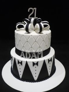 a two tiered cake decorated with black and white bow ties, the number 21