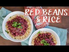 two white bowls filled with red beans and rice on top of a wooden table next to a bag of peanuts