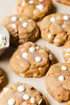 several cookies with white chocolate chips on top and one cookie in the middle, next to a bowl of marshmallows