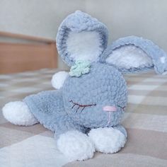 a blue stuffed animal laying on top of a checkered tablecloth covered bedding