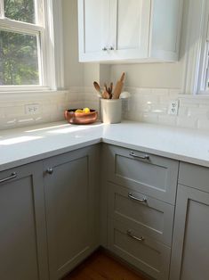 the corner of a kitchen with white cabinets and counter tops is pictured in this image