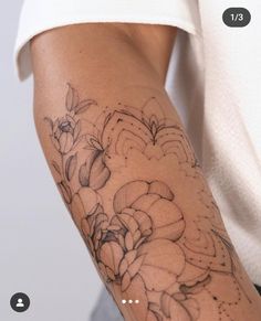 a woman's arm with flowers on it and dots in the background that are black and white