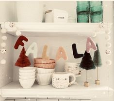 a shelf filled with cups and mugs covered in felt letters that spell out the word fala