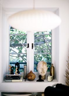 a window sill filled with books and vases next to a lamp on top of a table