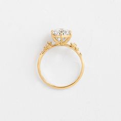 a yellow gold engagement ring with an oval cut diamond in the center and small diamonds around the band