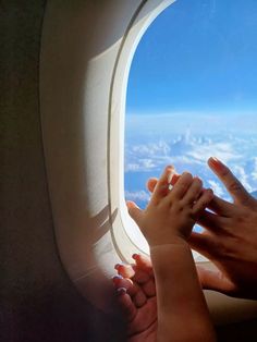 two people holding hands while looking out an airplane window