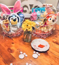 two baskets filled with stuffed animals sitting on top of a wooden table next to flowers