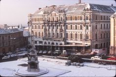 an old building with snow on the ground and cars parked outside in front of it