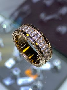 a gold ring with white and yellow diamonds on it's side sitting on a table