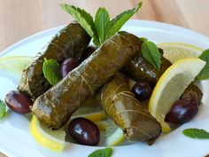 some olives and lemon are on a plate with minty garnishes