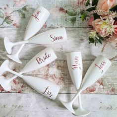 four wine glasses with names on them sitting next to some flowers and a vase filled with pink roses