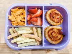 a plastic container filled with different types of food on top of a wooden table next to fries and strawberries