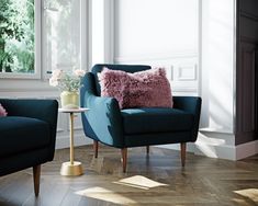 a living room with two blue chairs and a pink pillow on the armrests