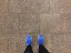 a person with blue shoes standing on a sidewalk