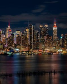 the city skyline is lit up at night with bright lights on it's skyscrapers