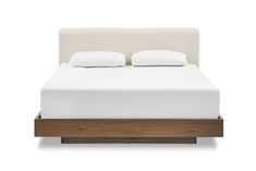 a bed with white sheets and pillows on it's headboard, in front of a white background