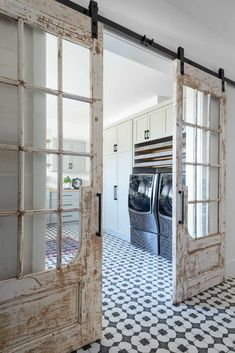 an open door leading to a washer and dryer in a room with black and white tile flooring