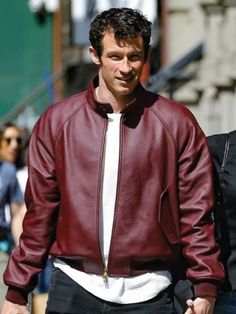 a man in a red leather jacket walking down the street with his hand in his pocket