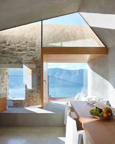 a bowl of fruit sitting on top of a wooden table in front of a window