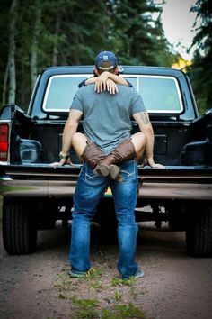 a man holding his dog in the back of a pickup truck