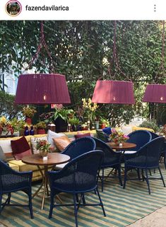 an outdoor seating area with blue chairs and yellow tablecloths, surrounded by greenery