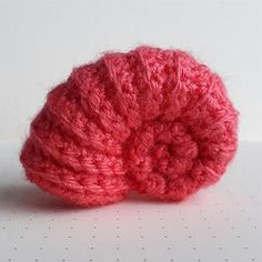 a pink crocheted object sitting on top of a table