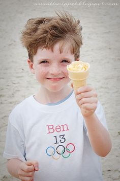 a young boy holding an ice cream cone in his hand and smiling at the camera