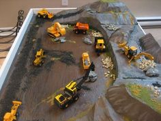 there are many construction vehicles on the model train track that is made out of legos