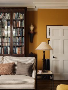 a living room filled with furniture and bookshelves next to a lamp on a table