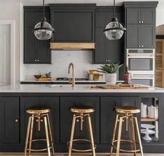 three stools are in the middle of a kitchen with black cabinets and white countertops