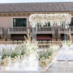 an outdoor wedding setup with white flowers and greenery in front of a large building