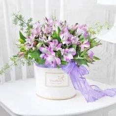 a flower pot with purple flowers on a white table