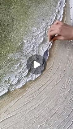 a person is painting the side of a wall with green and white paint on it