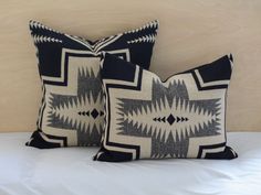 two black and white pillows sitting on top of a bed