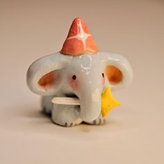 an elephant figurine with a hat on its head holding a piece of food