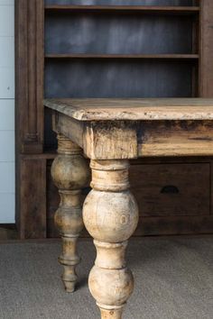 an old wooden table sitting in front of a book shelf