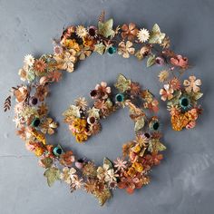 an arrangement of flowers and leaves arranged in the shape of a circle on a gray surface