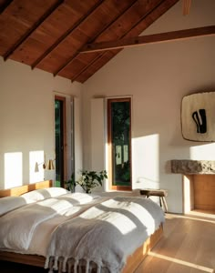 a bed sitting under a wooden ceiling in a bedroom next to two windows and a fire place