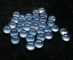 several blue and white glass beads on a black surface with one light reflecting off the top