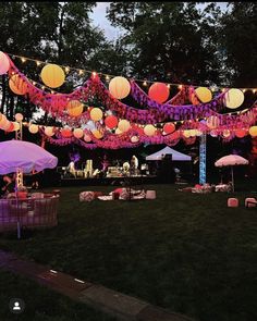 an outdoor party with paper lanterns and umbrellas in the evening light, on grass