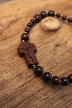 +.This is a rosary bracelet made of wood. The crucifix and the beads are constructed of wood. +.The wooden rosary is beneficial because you can feel the softness of the wood while praying. The more you contact wood, the more it takes on a natural brilliance. +.Surinamese ebony was used to make the crucifix. The light brown tone of Surinamese ebony is appealing. Surinamese ebony is so hard that it may be carved finely. It is carved over a long period of time rather than molded for a few minutes. Brown Crucifix Jewelry For Gifts, Brown Crucifix Jewelry Gift, Spiritual Cross Bracelet For First Communion, Spiritual Cross Bracelets As Gifts, Adjustable Hand-strung Rosary As Gift, Adjustable Spiritual Rosary As Gift, Handmade Cross-shaped Rosary Bracelet For Blessing, Handmade Cross Rosary Bracelet For Blessing, Spiritual Rosary Bracelet With Round Beads As Gift