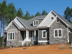 a house that is made out of stone and has white trim on the front windows