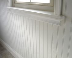 an empty window sill in the corner of a room with white paneling on the walls