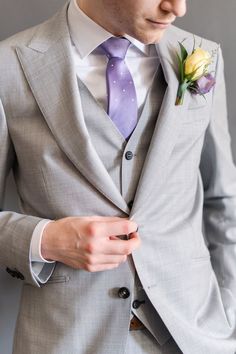 a man in a gray suit with a purple tie and flower boutonniere